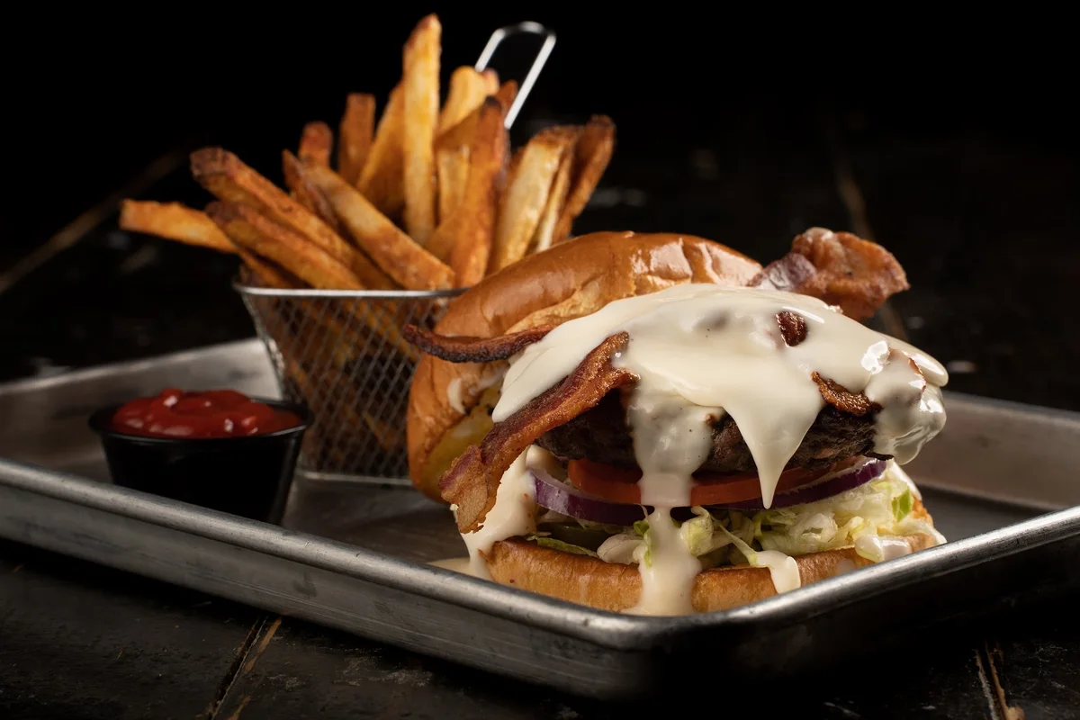The Hot Mess burger, bacon and lettuce under a pour of queso