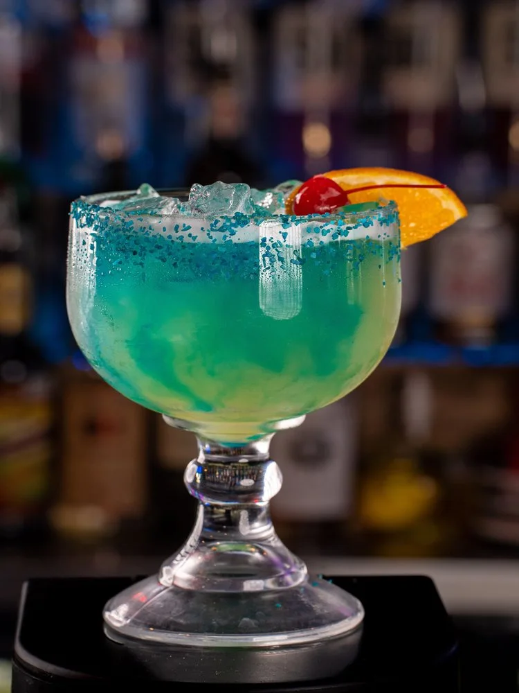 The Blu-Rita, a blue margarita in a goblet with a cherry and orange