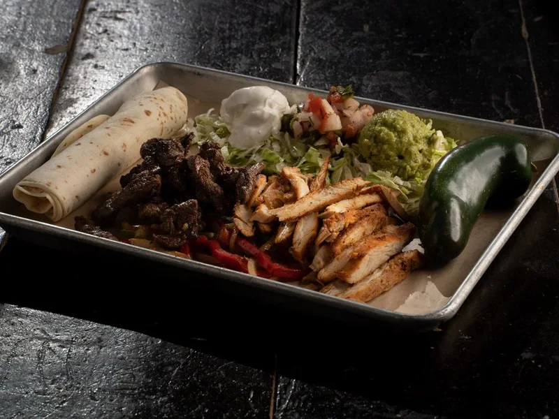Fajita plate with grilled peppers, guacamole and a roasted jalapeno