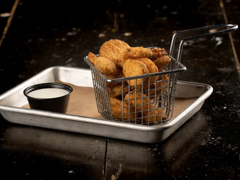 Fried pickle chips in a wire basket with ranch