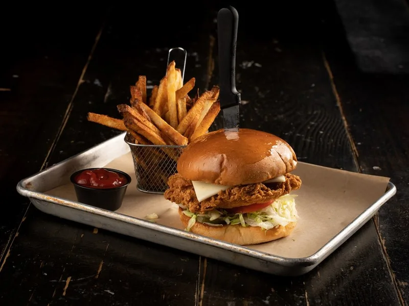 Country fried sandwich with swiss cheese, lettuce and tomato