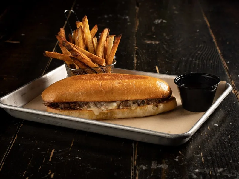 French dip on a hoagie roll with a cup of au jus