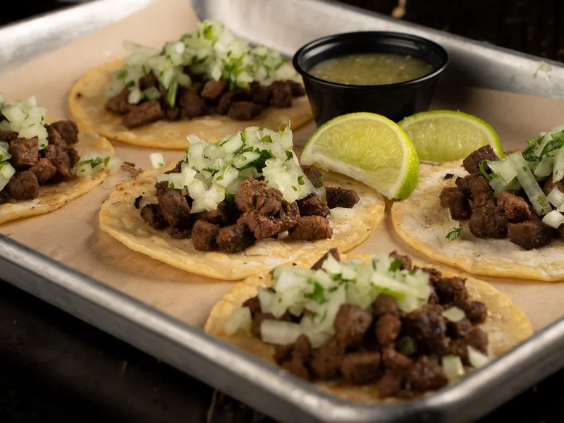 Street tacos on corn tortillas with onion, cilantro, lime and salsa verde